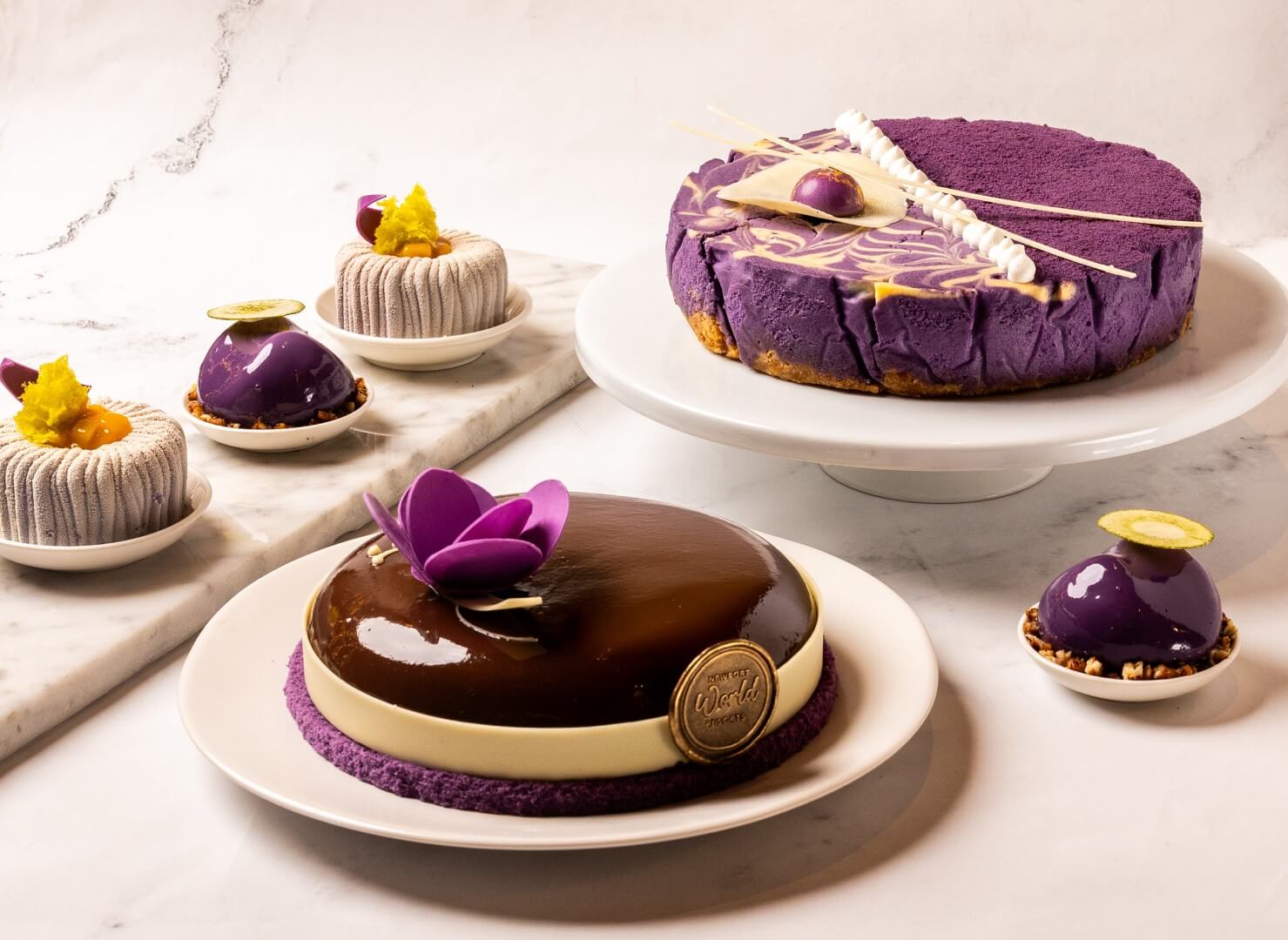 Garden Wing Café presents a selection of ube-inspired desserts, featuring Ube Pecan Chocolate Cake and Ube Coconut Cheesecake alongside individually plated desserts Golden Purple and Velvet Earth
